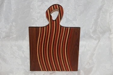 Striped hardwood cutting board with a curved handle